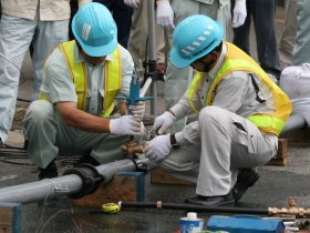 写真：水道管に分水器を取り付ける作業員
