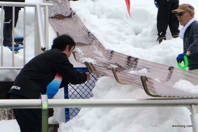 写真：波板をフェンスに固定する様子（NDソフトスタジアム山形除雪作業１日目）