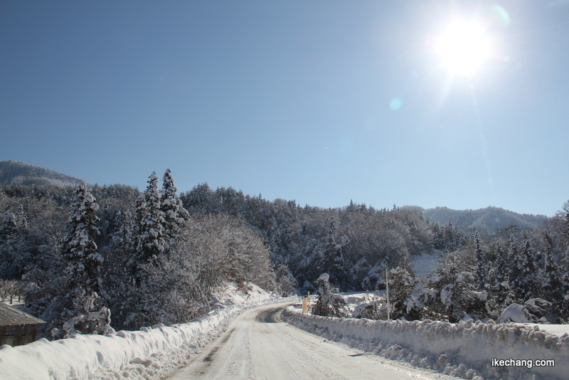 画像：青い空と白い山々と雪道