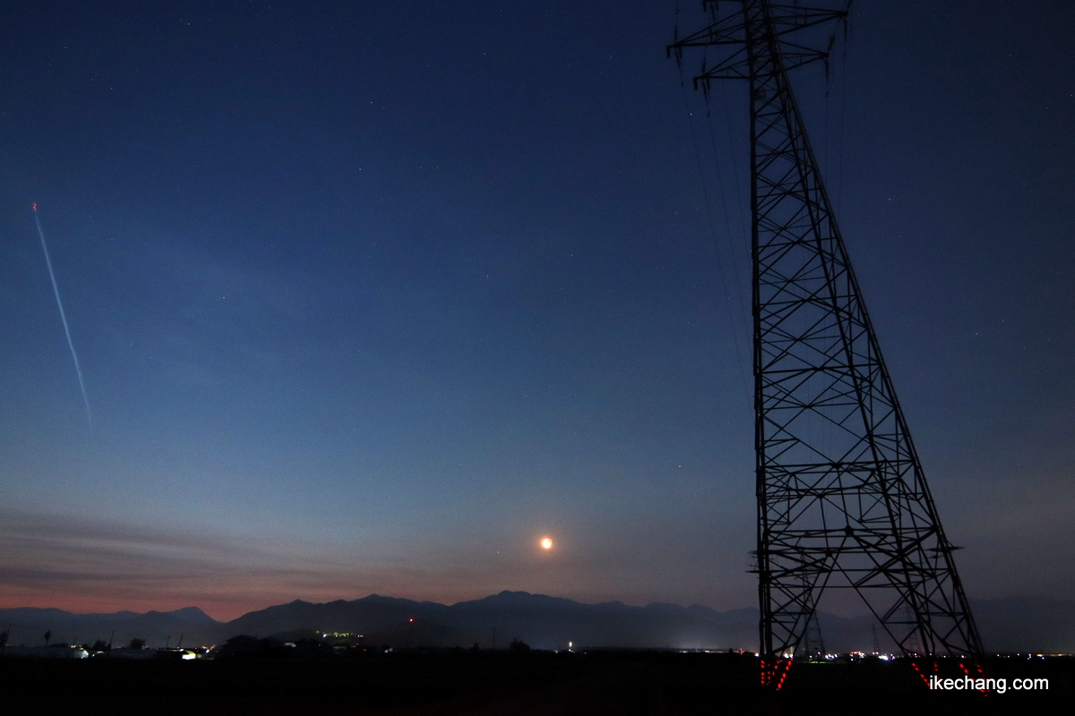 写真：東の空から登ってきた細い月と鉄塔と飛行機雲