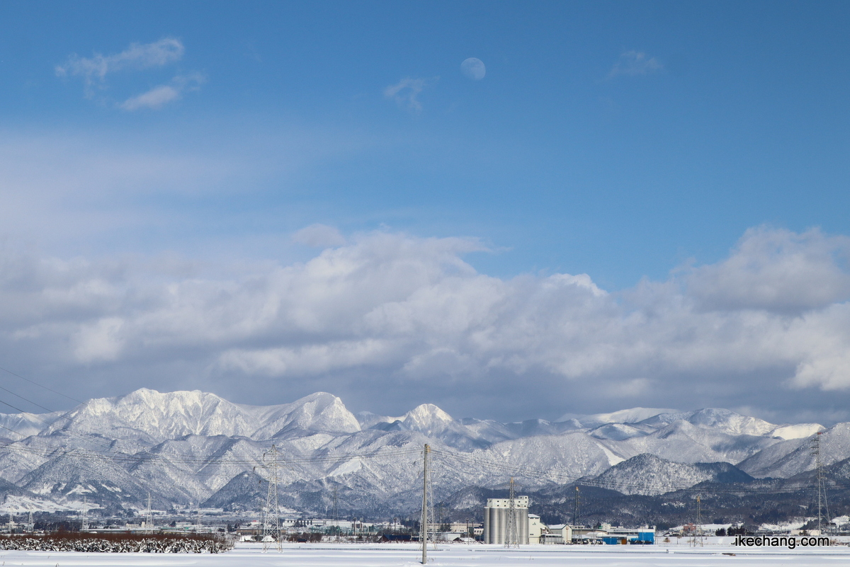 写真：青い空に輝く白い山々と月